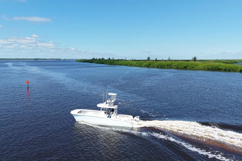  Yacht Photos Pics 2020 Tideline 365 Offshore boat cruising on a serene river under a clear blue sky.