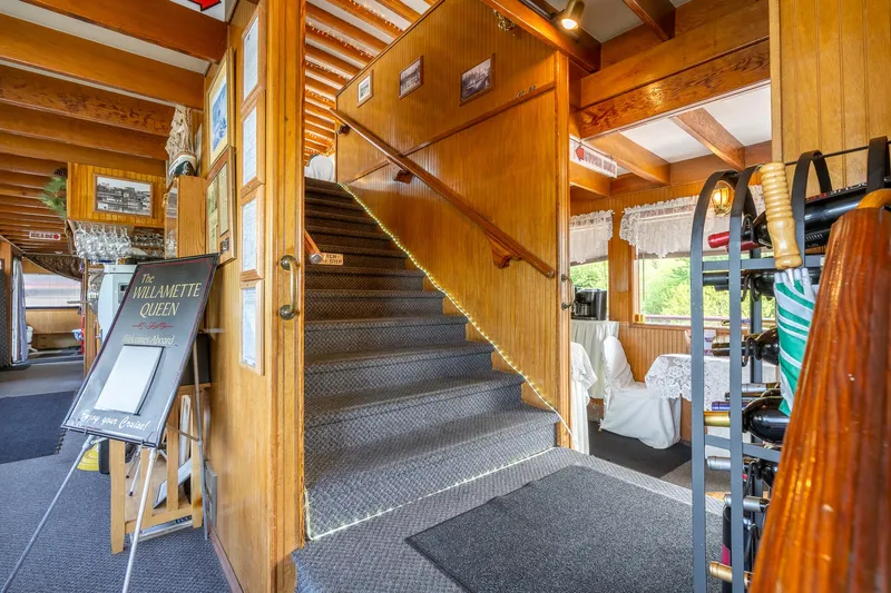 Willamette Queen Yacht Photos Pics Interior of 1990 Howdy Eidelman Sternwheeler, featuring wooden staircase and dining area.
