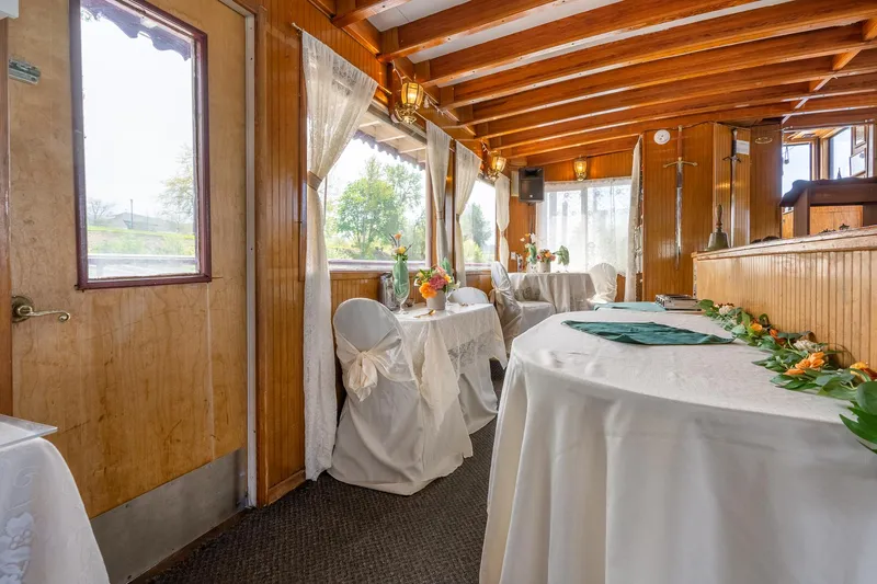Willamette Queen Yacht Photos Pics Elegant interior of 1990 Howdy Eidelman Sternwheeler, featuring decorated tables and wooden beams.