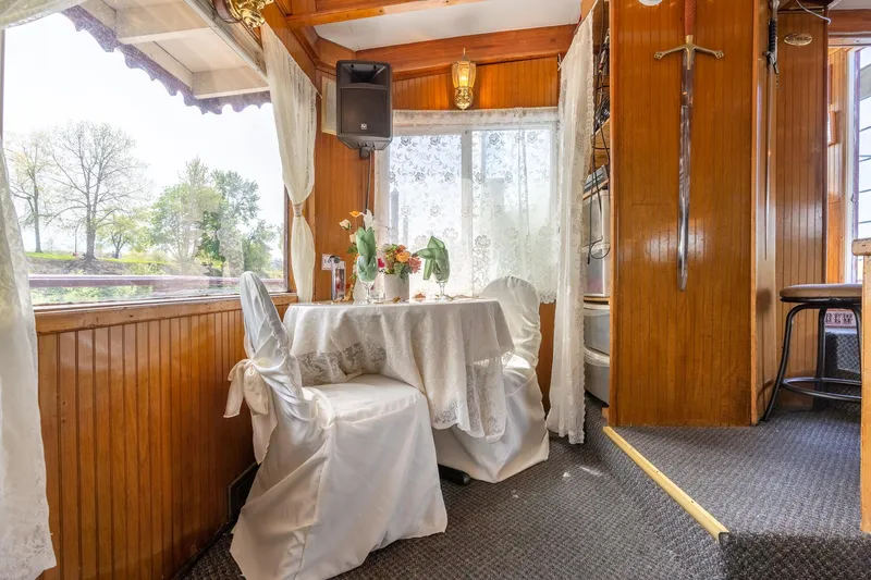 Willamette Queen Yacht Photos Pics Elegant dining area on 1990 Custom Howdy Eidelman Sternwheeler, featuring wooden interior and floral decor.