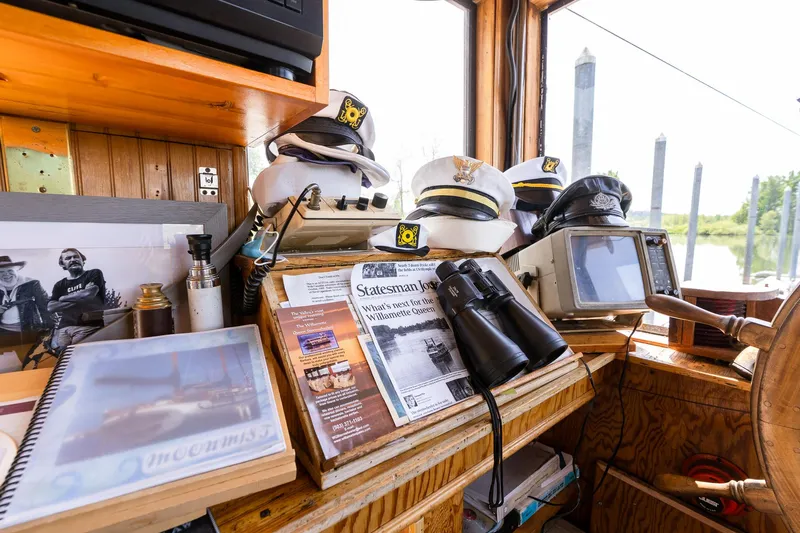 Willamette Queen Yacht Photos Pics Pilothouse interior with captain hats, binoculars, and nautical charts on a 1990 Howdy Eidelman Sternwheeler.