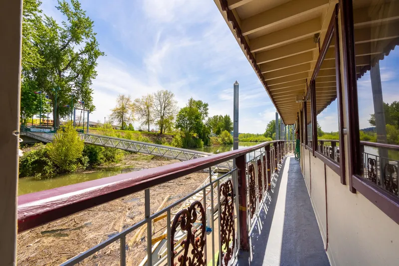 Willamette Queen Yacht Photos Pics Side view of 1990 Howdy Eidelman Sternwheeler, showcasing deck and scenic river landscape.