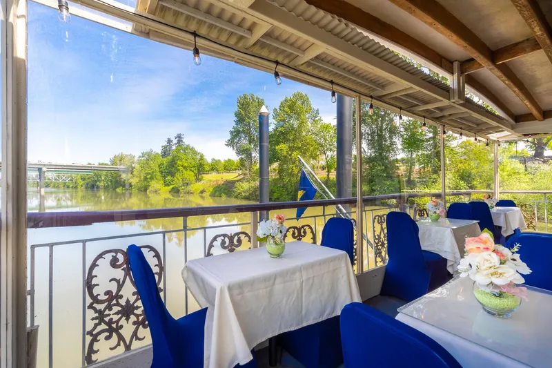 Willamette Queen Yacht Photos Pics Elegant dining area on 1990 Howdy Eidelman Sternwheeler, overlooking serene river and lush greenery.