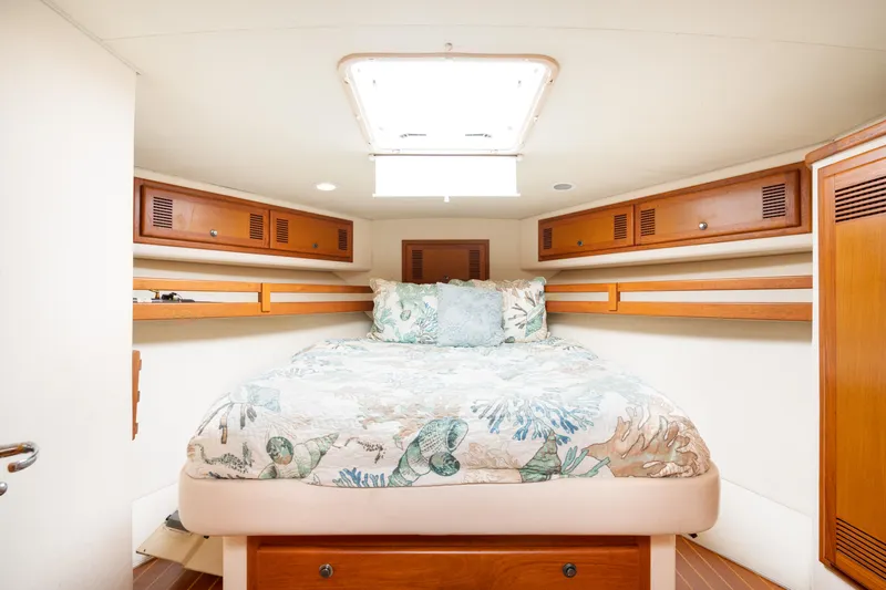 Fancy Yacht Photos Pics Cozy cabin interior of 2000 Cabo 45 Express with bed and wooden storage.