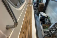 Nimbus 345 Coupe 2001 boat deck with wooden finish and metal railing in a workshop.