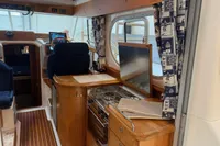 Interior of 2001 Nimbus 345 Coupe boat with wooden cabinetry and nautical-themed curtains.