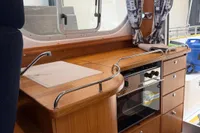 Interior of 2001 Nimbus 345 Coupe boat kitchen with wooden cabinetry and oven.
