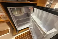 Open refrigerator inside 2001 Nimbus 345 Coupe boat, featuring wooden interior.