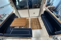 Interior of 2001 Nimbus 345 Coupe with wooden table and blue cushioned seating.