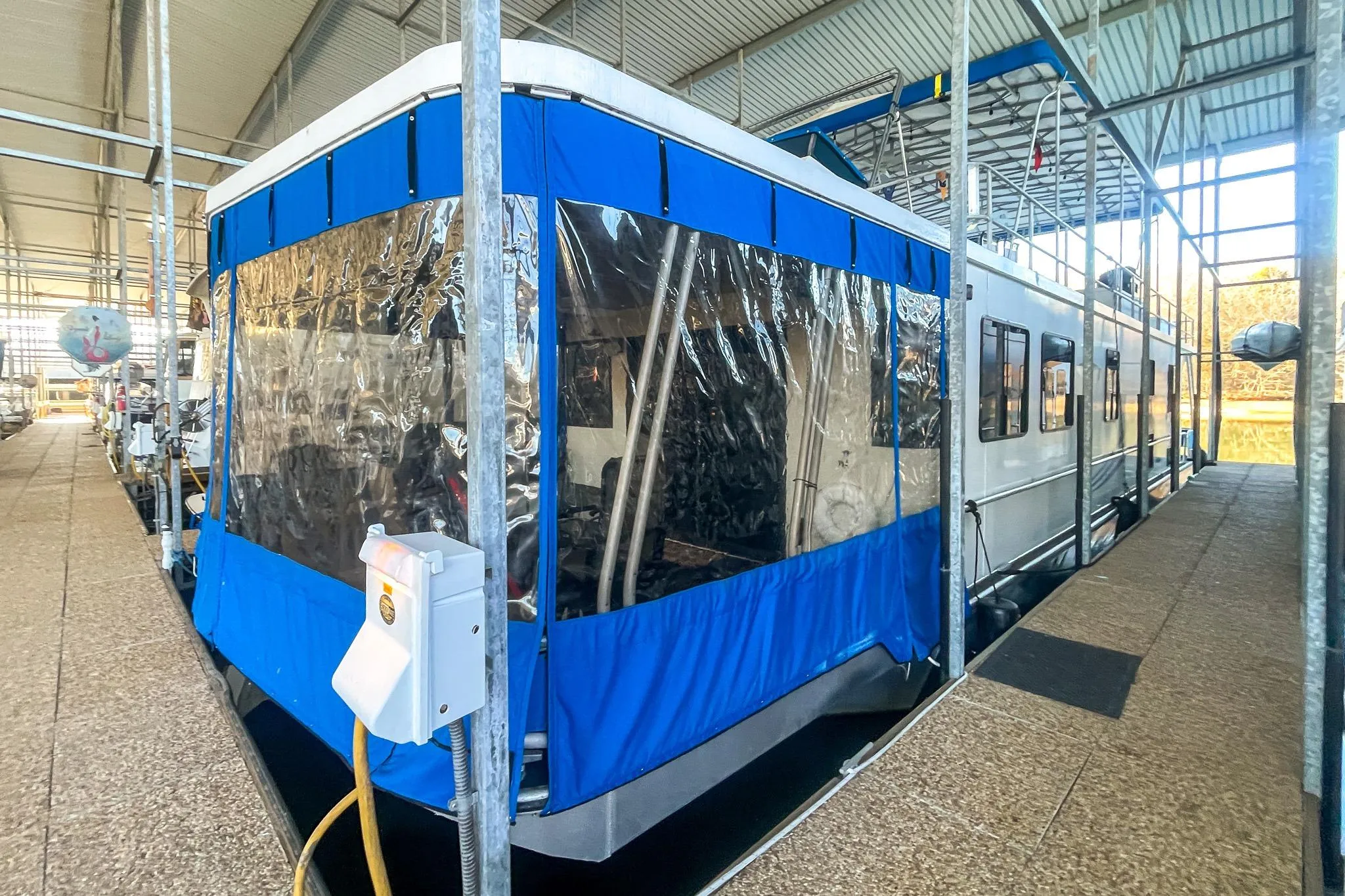 1996 Lakeview 66 x 16 Widebody Houseboat docked with blue canopy in marina.
