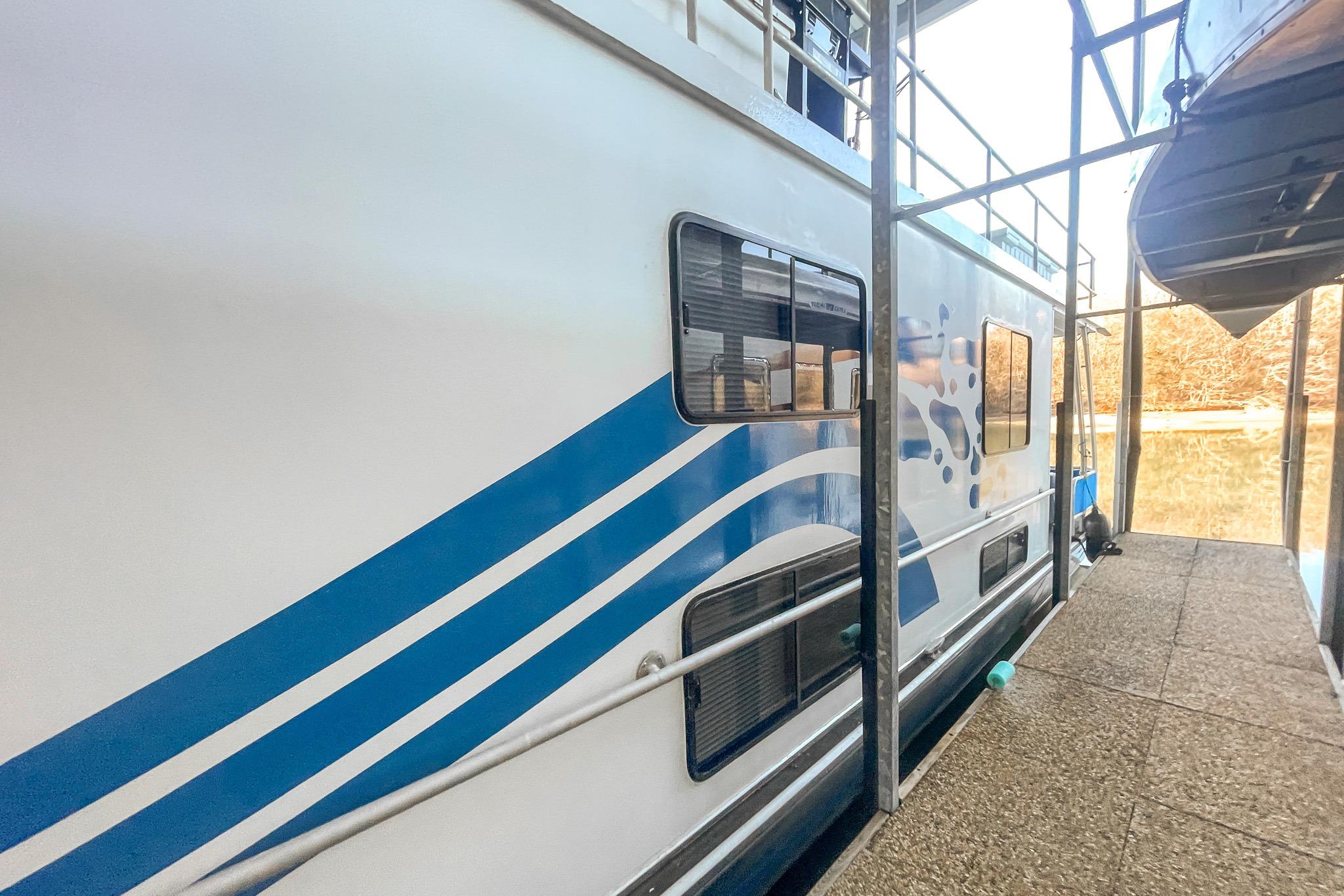1996 Lakeview 66 x 16 Widebody Houseboat docked, featuring blue wave design.