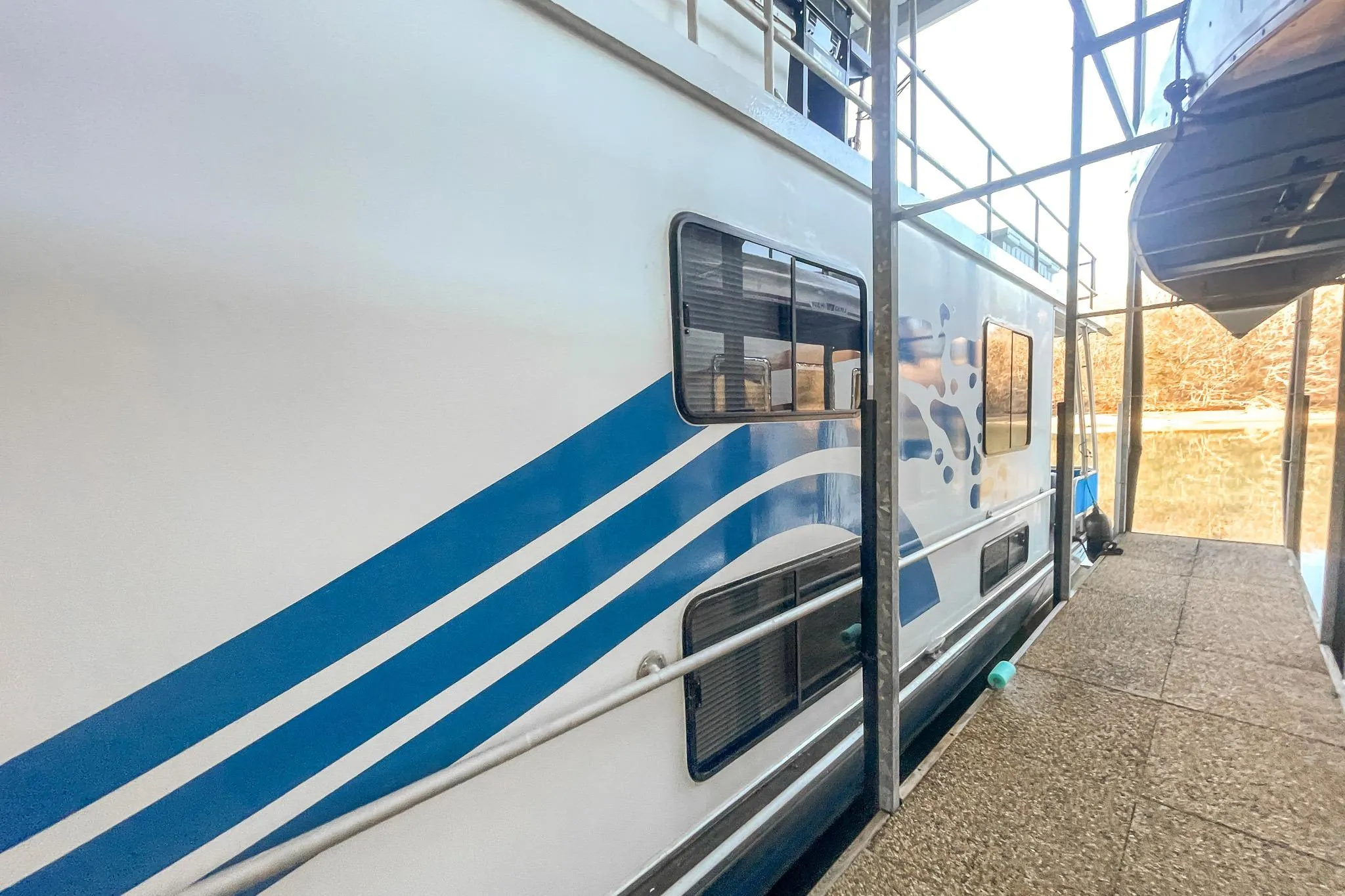1996 Lakeview 66 x 16 Widebody Houseboat docked, featuring blue wave design.