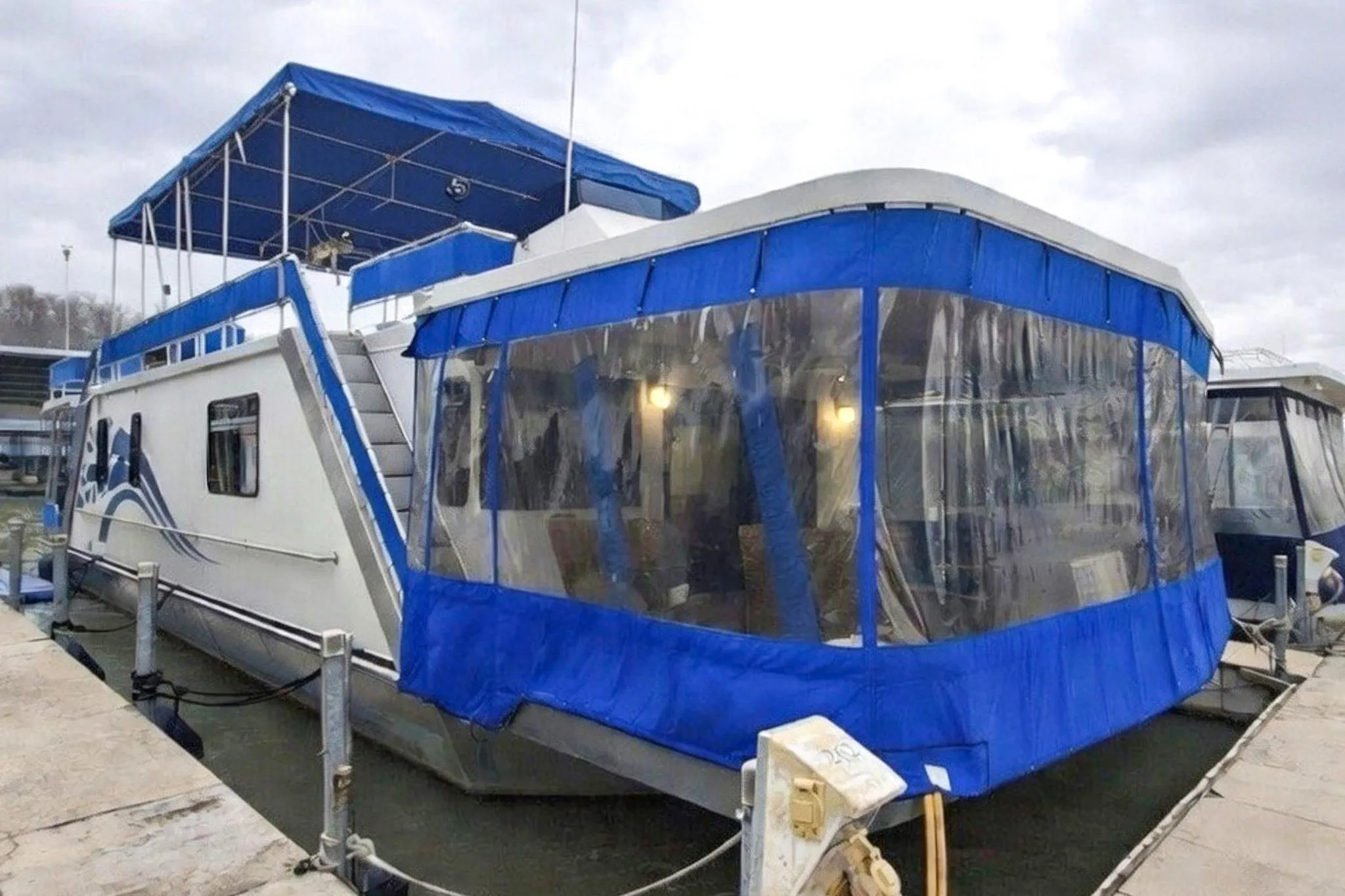 1996 Lakeview 66 x 16 Widebody Houseboat with blue canopy docked at marina.