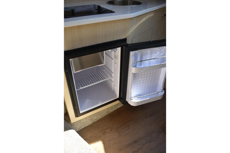  Yacht Photos Pics Open mini fridge in 2026 Regal 26 XO boat interior, showcasing compact storage space.