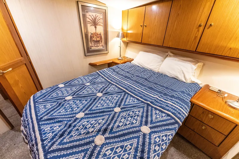  Yacht Photos Pics Cozy bedroom in 2006 Ocean 57 yacht with blue patterned bedding and wooden cabinets.