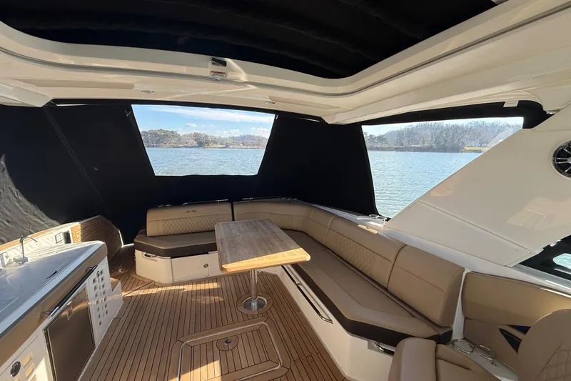  Yacht Photos Pics Luxurious 2022 Sea Ray SLX 400 boat interior with seating and table, overlooking serene water.