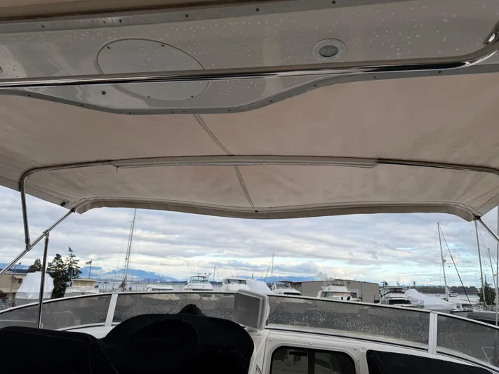  Yacht Photos Pics 2003 Meridian 490 Pilothouse boat with canopy, docked at marina under cloudy sky.