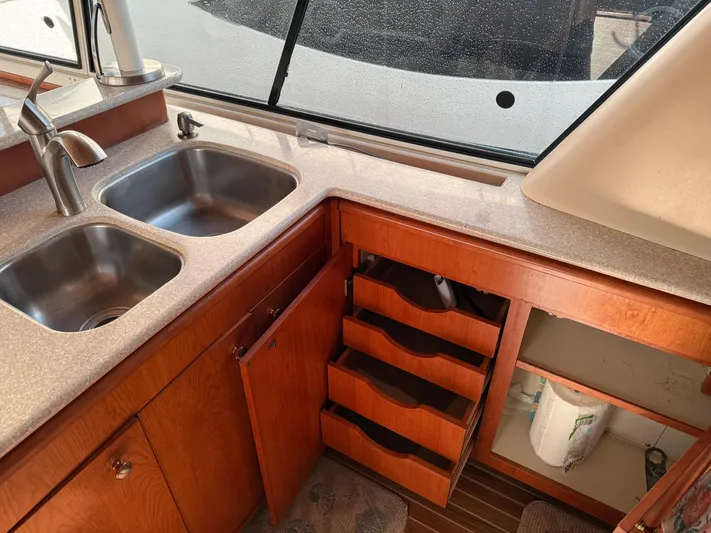  Yacht Photos Pics 2003 Meridian 490 Pilothouse kitchen with double sink, wooden cabinets, and open storage.