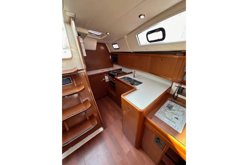 Shamrock Yacht Photos Pics Interior of 2011 Beneteau Oceanis 40 sailboat, featuring a compact kitchen with wooden cabinetry.