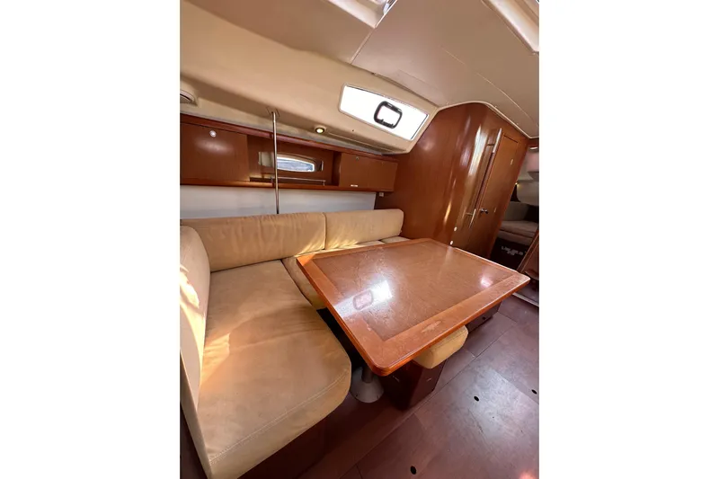 Shamrock Yacht Photos Pics Interior of 2011 Beneteau Oceanis 40 yacht with wooden table and beige seating.