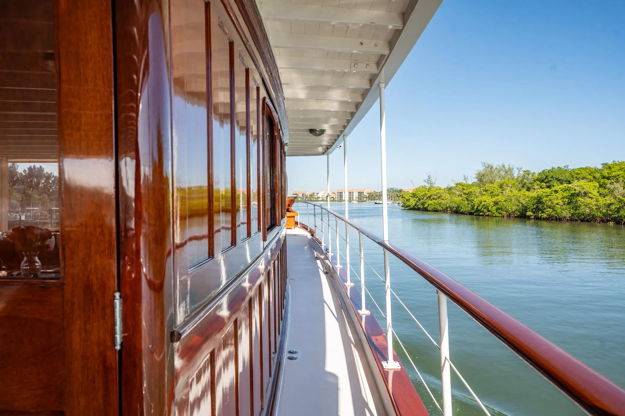 Side view of a 1937 Trumpy 58 yacht with polished wood and scenic waterway.