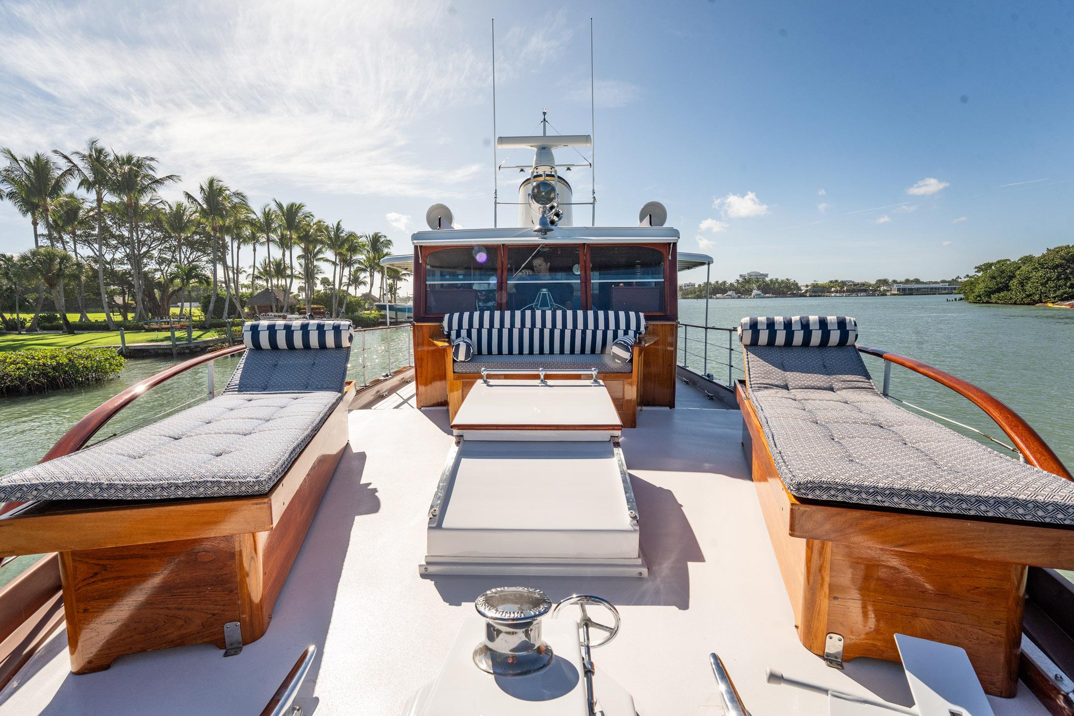 Luxurious 1937 Trumpy 58 yacht deck with elegant seating and scenic waterfront view.