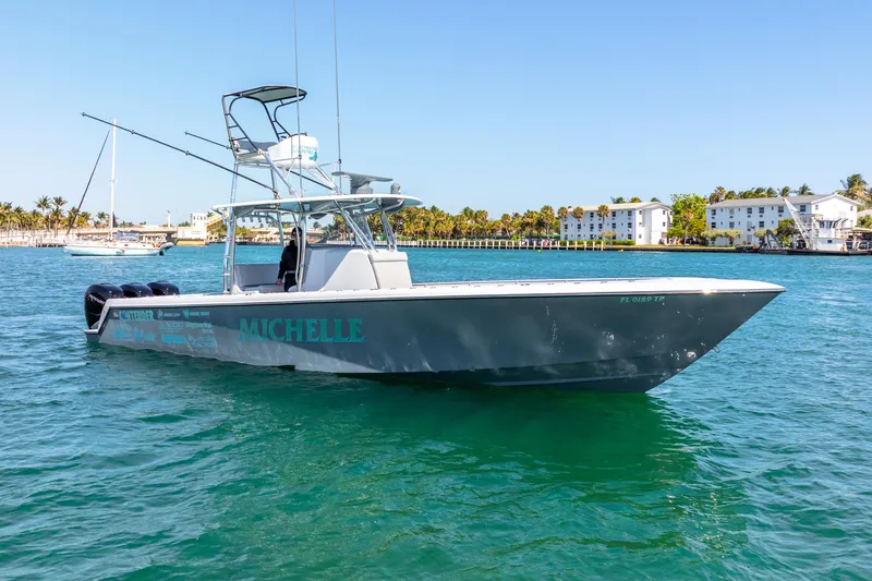  Yacht Photos Pics 2023 Contender 39ST boat on clear blue water near coastal buildings.