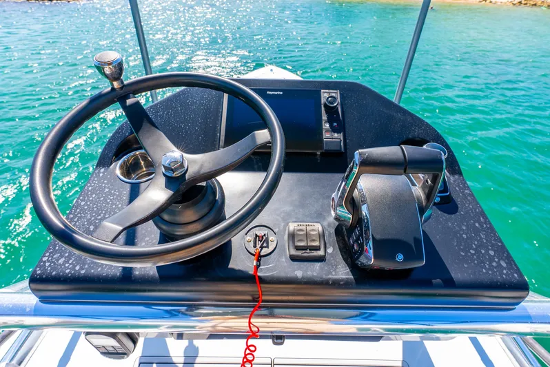  Yacht Photos Pics Helm of 2023 Contender 39ST boat with steering wheel and controls, on clear blue water.