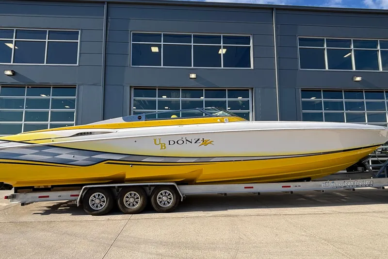  Yacht Photos Pics 2002 Donzi 45 ZX speedboat in yellow and white on a trailer, parked outside a building.