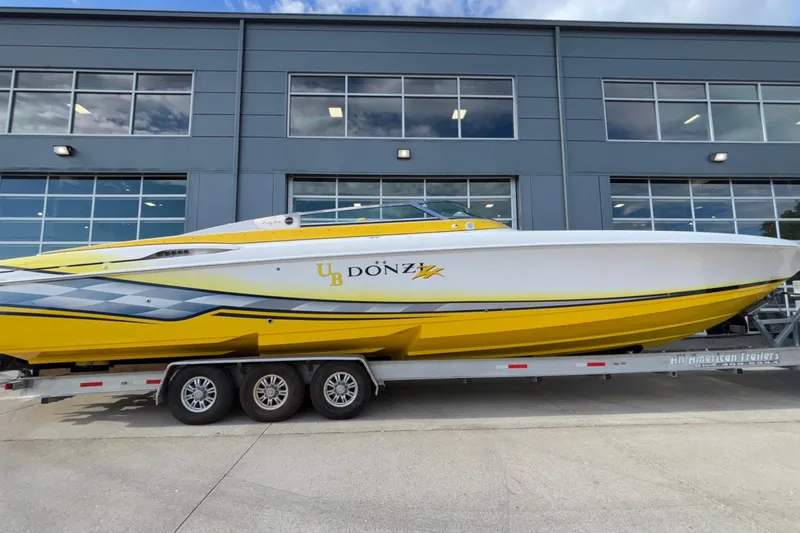  Yacht Photos Pics 2002 Donzi 45 ZX powerboat in vibrant yellow on a trailer, parked outside a modern building.