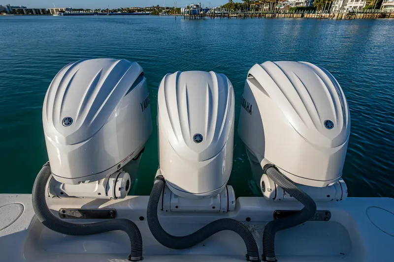 Wunderbar Yacht Photos Pics Triple Yamaha outboard engines on a 2022 Contender 39 ST boat, docked on calm water.