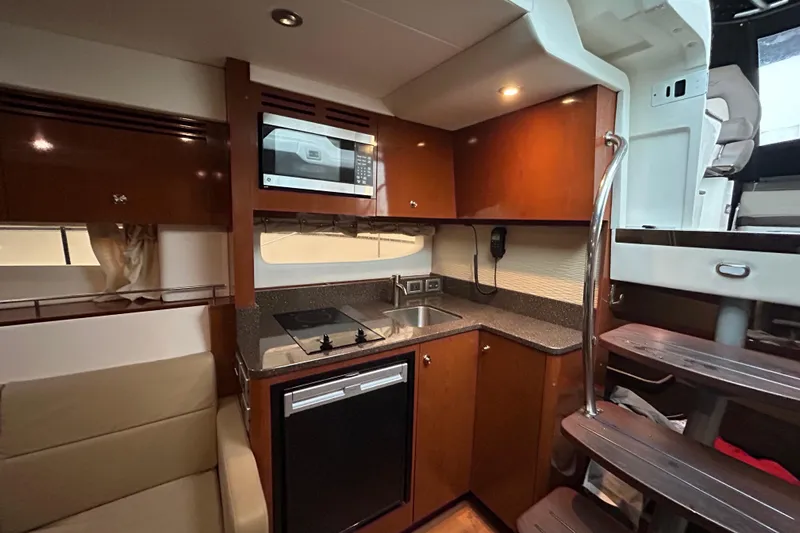  Yacht Photos Pics 2014 Sea Ray 350 Sundancer yacht interior kitchen with microwave, stove, and wooden cabinetry.