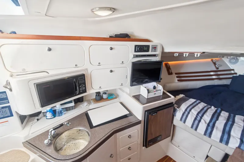 Pole Position Yacht Photos Pics 2006 Grady-White Express 330 cabin interior with kitchenette, microwave, and cozy sleeping area.