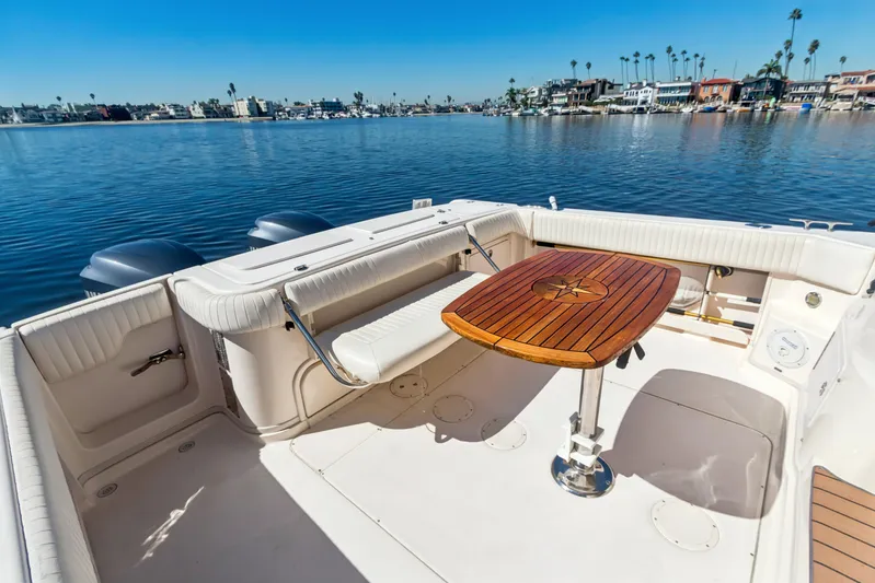 Pole Position Yacht Photos Pics 2006 Grady-White Express 330 boat deck with wooden table, overlooking calm waters and coastal scenery.
