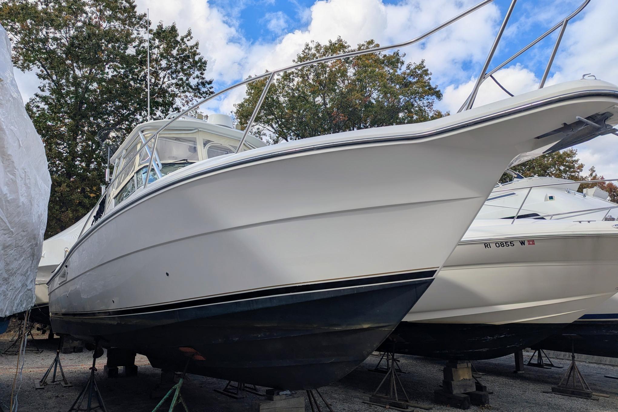 2002 Stamas 340 Express boat on stands, surrounded by trees and blue sky.