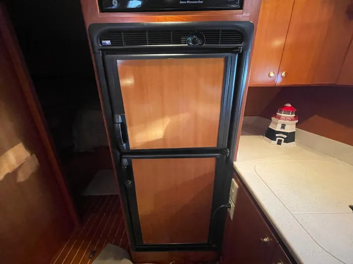 The Lucky Dreamers Yacht Photos Pics 2005 Novatec 48 Cockpit Motor Yacht kitchen with wooden cabinetry and compact refrigerator.