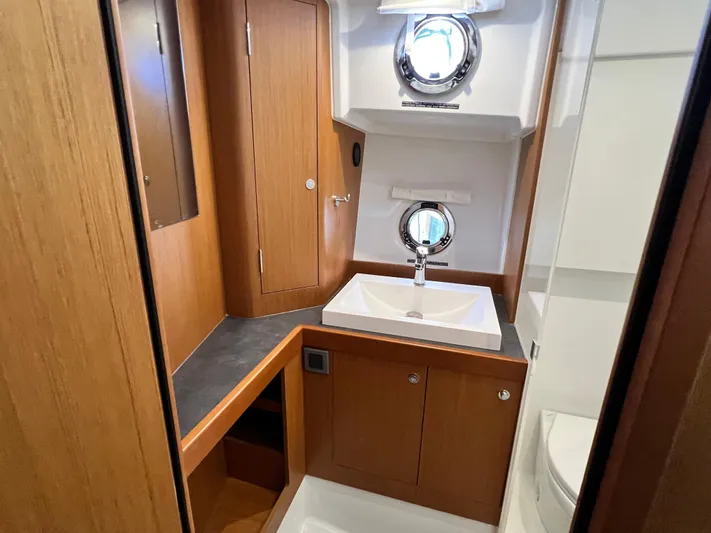  Yacht Photos Pics 2021 Beneteau Swift Trawler 35 bathroom with wooden cabinetry and porthole windows.