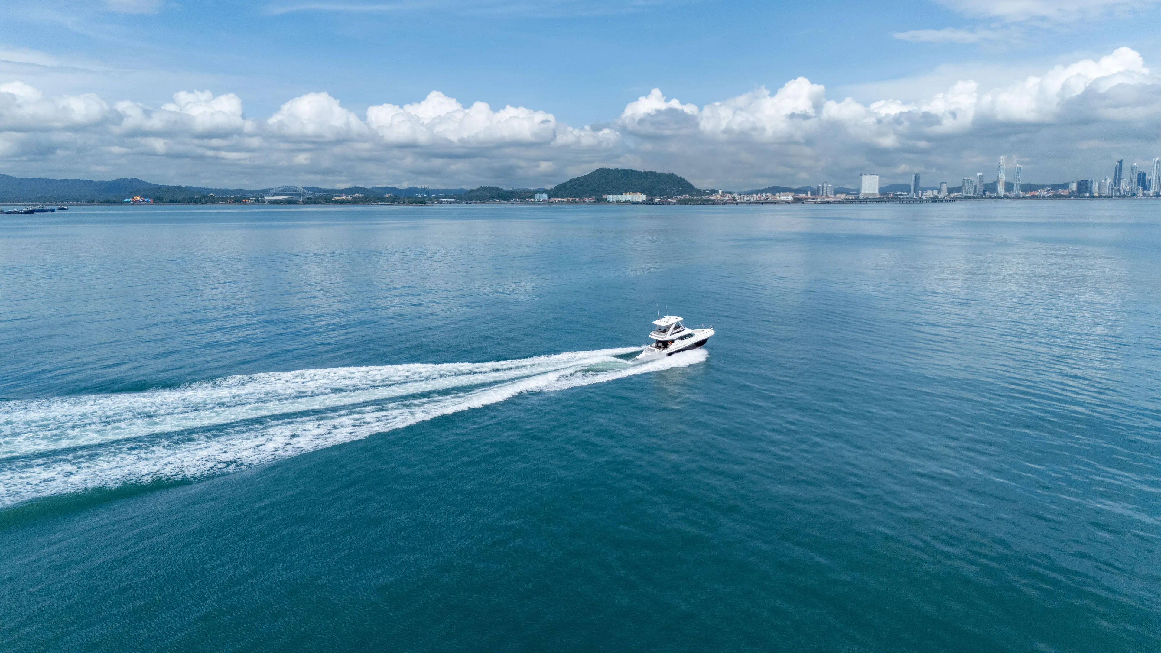  Yacht Photos Pics 2019 Tiara Yachts F44 Flybridge cruising on open water with city skyline in background.
