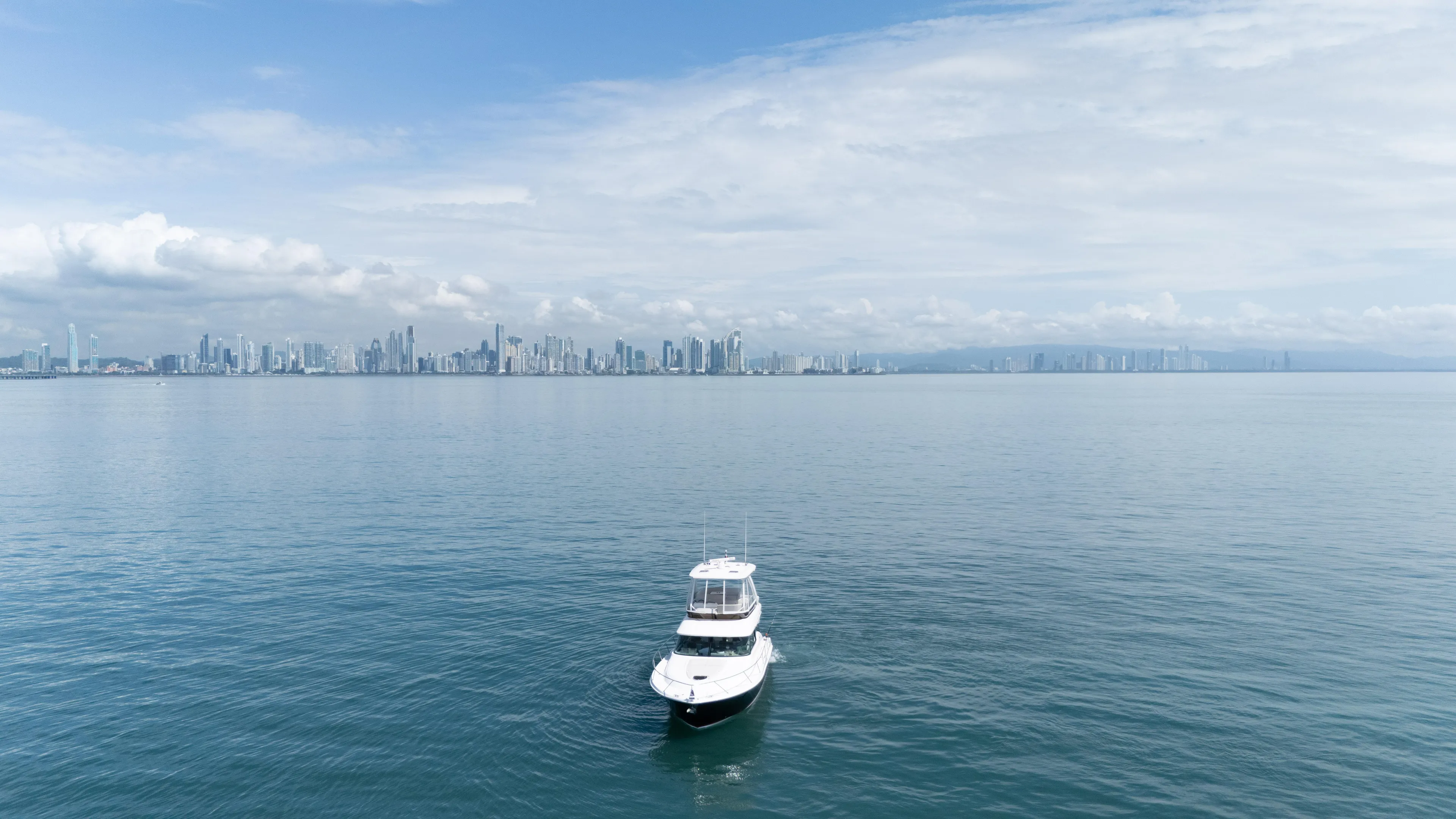  Yacht Photos Pics 2019 Tiara Yachts F44 Flybridge on calm sea with city skyline in background.