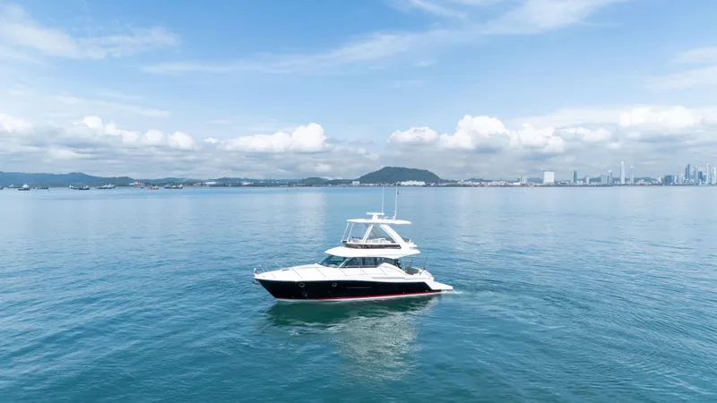  Yacht Photos Pics 2019 Tiara Yachts F44 Flybridge on calm sea with city skyline in background.