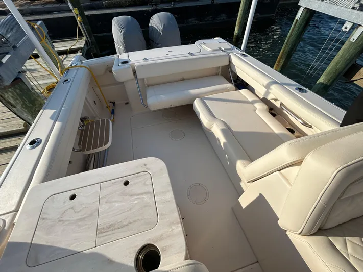  Yacht Photos Pics 2023 Grady-White Freedom 275 boat interior with seating and storage, docked by the water.