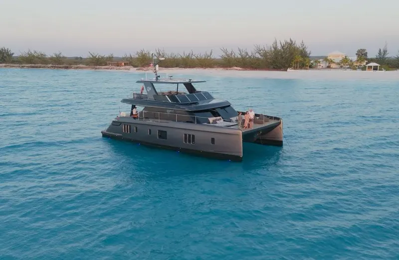  Yacht Photos Pics 2024 Sunreef 60 Eco yacht cruising in clear blue waters near a tropical shoreline.