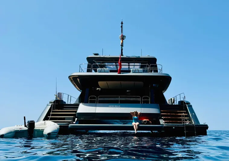  Yacht Photos Pics 2024 Sunreef 60 Eco yacht on open water, rear view with swimmer.