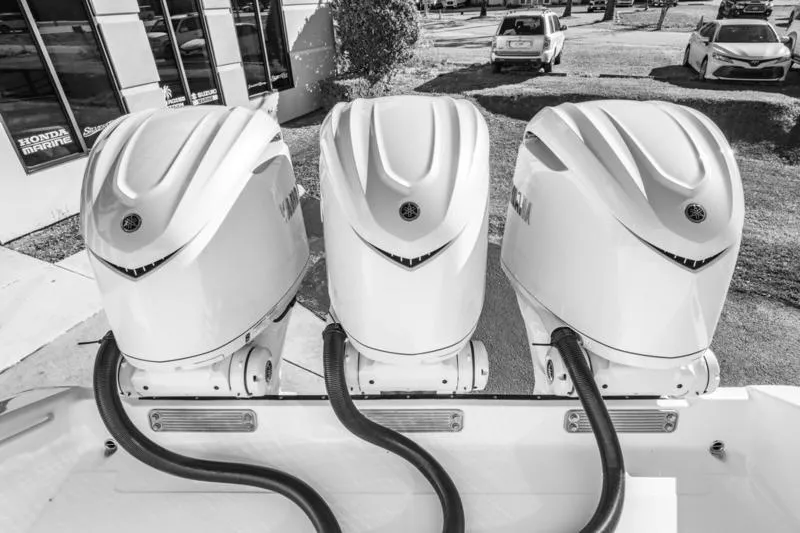  Yacht Photos Pics Triple outboard engines on a 2025 Edgewater 370CC boat, parked outdoors.