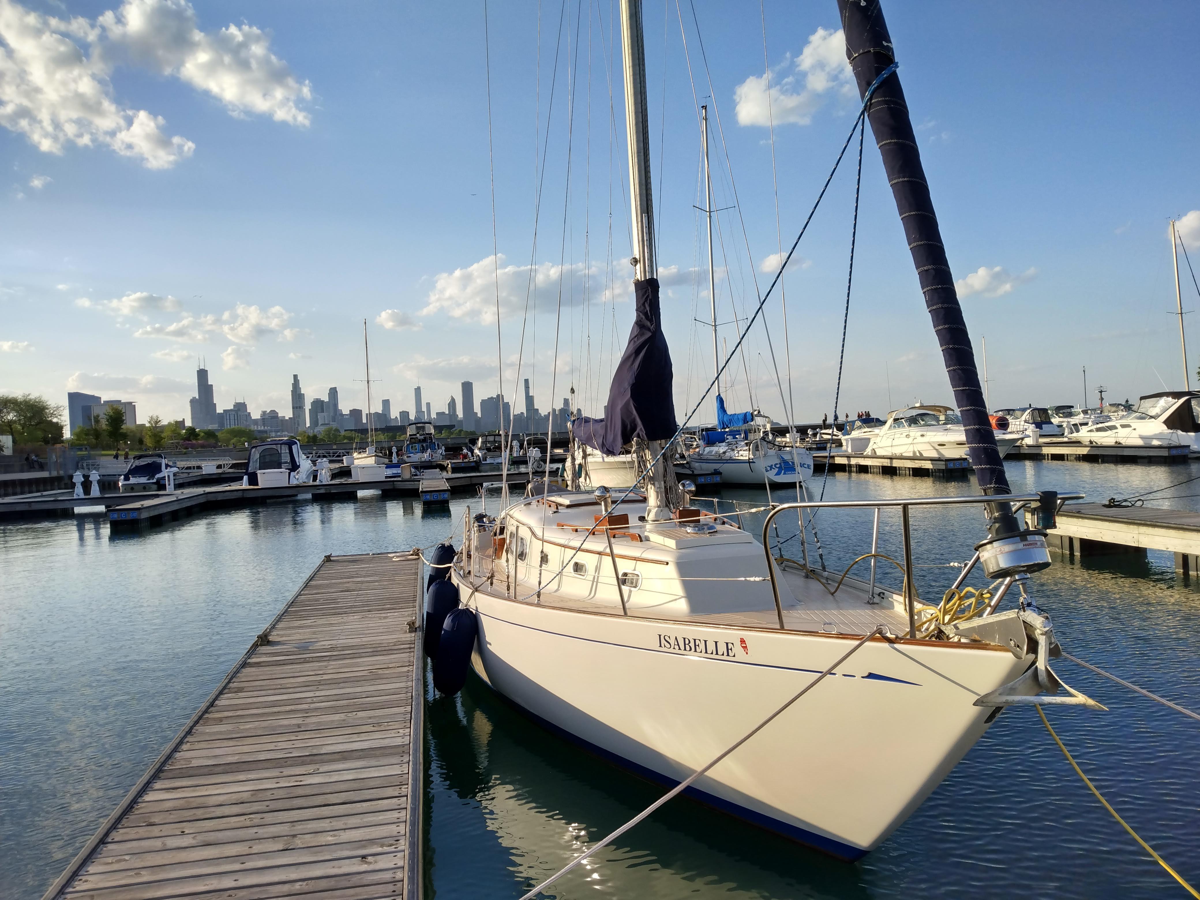 1969 Chris-Craft Apache 37 sailboat docked in marina with city skyline in background.
