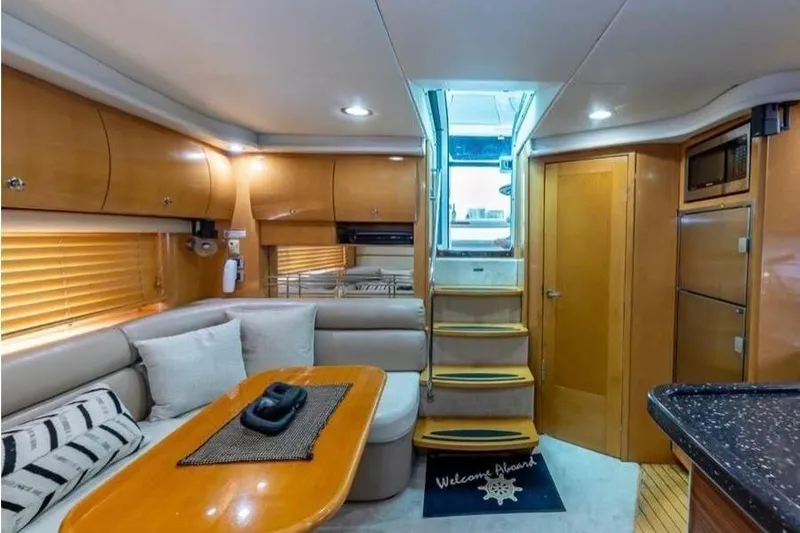  Yacht Photos Pics 2009 Four Winns V458 yacht interior with cozy seating, wooden cabinetry, and stairs leading to deck.
