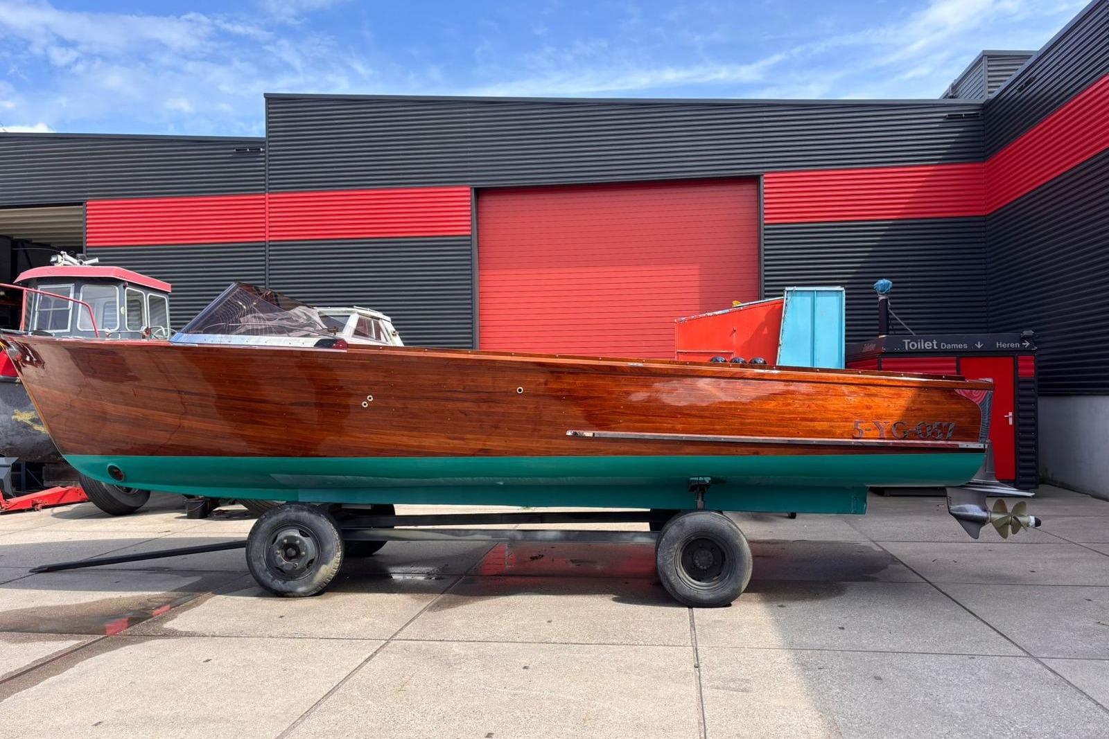 Vintage 1953 Barca Di Legno Italiana 30 wooden boat on trailer, dockside setting.