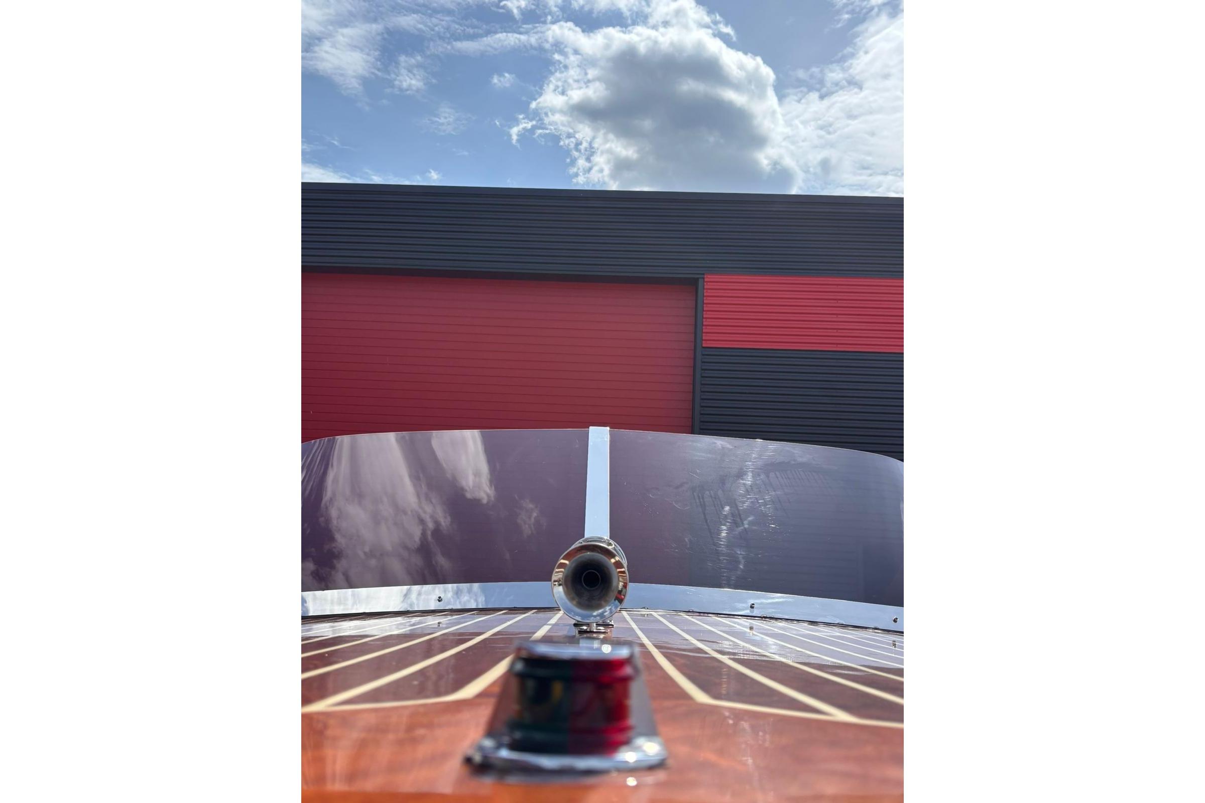 1953 Barca Di Legno Italiana 30 boat with wooden deck and windshield, under a cloudy sky.