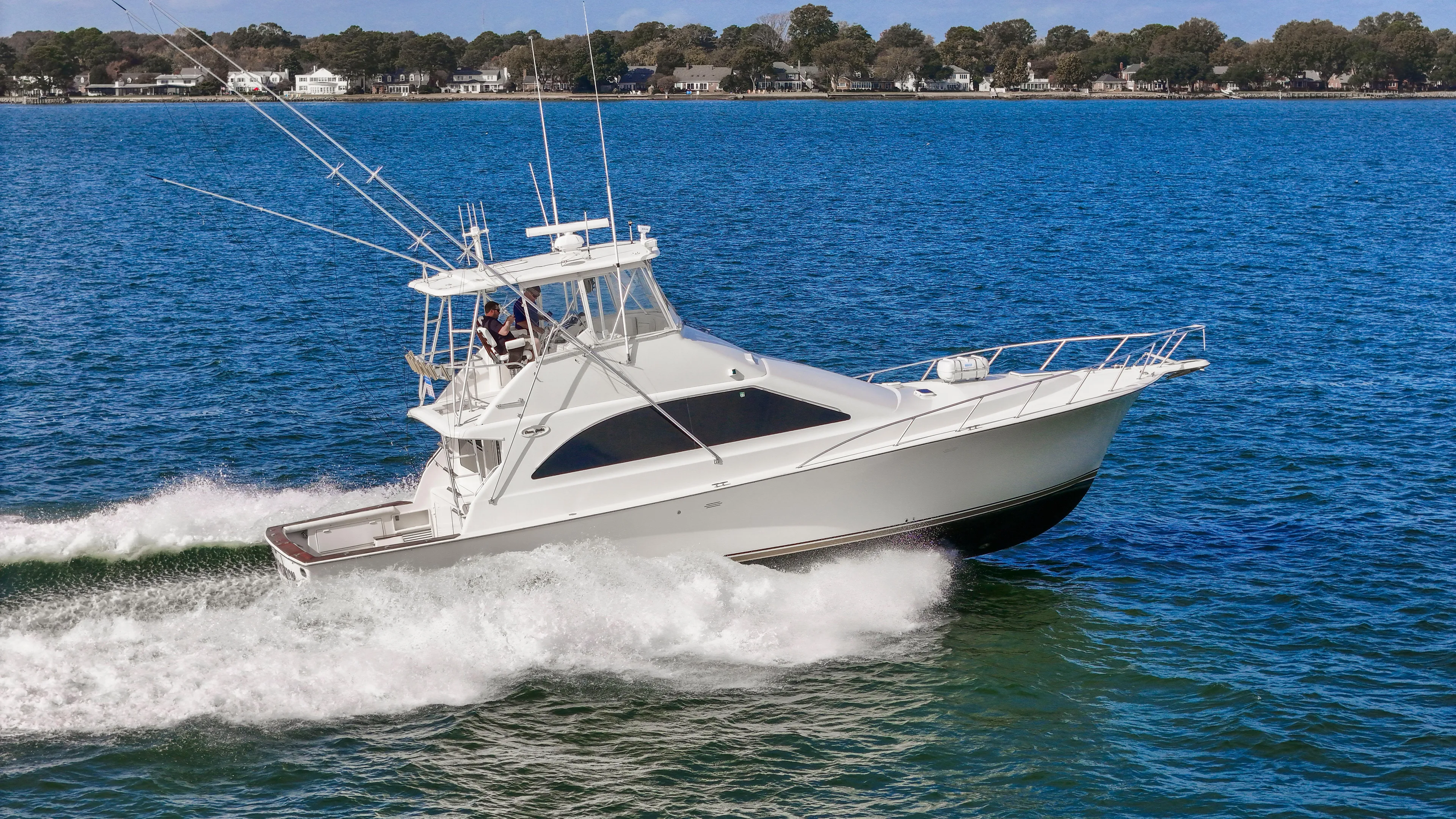 Event Horizon Yacht Photos Pics 2000 Ocean Yachts 48 Super Sport cruising on blue water near shoreline.