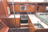 Interior of 2009 Dufour 45E Performance yacht kitchen with stove, sink, and wooden cabinetry.